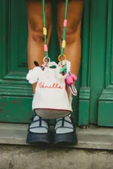 Cartera tipo tote bag de lona color crema con base rígida y cordón de ajuste superior. Tiene bordada la palabra "Vanilla" en color rojo.