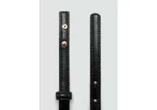 Cinturón fino de cuero sintético en color negro, con hebilla metálica rectangular de diseño minimalista en tono dorado.