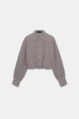 Camisa corta de manga larga con cuello solapa, confeccionada en tela con estampado de cuadros vichy en color bordó y blanco. Presenta un bolsillo delantero de plastrón, cierre frontal con botones y bajo abullonado con elástico interior.