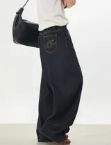 Jeans baggy de denim color azul oscuro, de corte ancho y relajado, con cintura semi-elástica en la parte trasera. Presenta bolsillos traseros con costuras a contratono y bordado de estrella en uno de ellos.