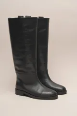 Bota de caña alta color marrón, confeccionada en cuero vacuno con forro y plantilla de cuero. Tiene suela de goma negra y un diseño de caña ancha.