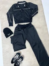 Campera deportiva negra con cierre frontal, cuello alto y detalles de líneas blancas en el pecho y mangas. Confeccionada en tejido técnico con puños y cintura elásticos.