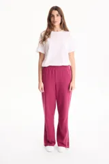 Pantalón deportivo negro de corte wide leg, sin frisa, con ribete blanco en los laterales y aberturas con botones en los tobillos.