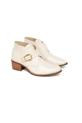 Botinetas de cuero charolado con textura croco en color off-white, con taco medio de efecto madera, punta redonda y tira lateral con hebilla metálica dorada.