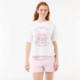 Pijama de dos piezas confeccionado en algodón, compuesto por una remera blanca de manga corta con estampado de Stitch y la frase 'You Make My Heart Smile', y un short rosado con finas rayas verticales blancas.