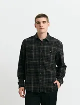 Camisa de franela a cuadros con cuello button-down, manga larga y botones de madera. Presenta dos bolsillos tipo parche en el frente con cierre de botón.