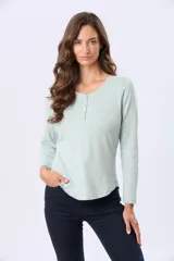 Remera de manga larga color negro, con cuello redondo y cierre frontal parcial con botones a tono. Presenta un diseño de corte recto con ruedo curvo.