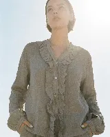 Camisa de lino color gris verdoso, con cuello mao, mangas largas y volados frontales decorativos que bordean la botonadura con botones de nácar.