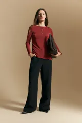 Top de manga larga con textura suave y leve brillo. Presenta una silueta al cuerpo, tajos laterales y terminaciones onduladas en el ruedo.