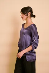 Blusa holgada de satén color beige, con escote en V y mangas largas con trabilla para sujetar remangadas.