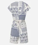 Enterito corto sin mangas de viscolino, con escote en V y estampado tipo patchwork en tonos blanco y azul marino, con motivos tropicales como palmeras y patrones geométricos. Incluye trabillas en la cintura y cinturón de cuerda trenzada.