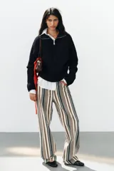 Jeans de tiro medio con diseño de rayas verticales en tonos beige, marrón y verde, corte boyfriend, cinco bolsillos y cierre frontal con cremallera y botón.