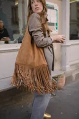 Maxi cartera tipo bolso de cuero gamuza natural color tostado, con flecos colgantes en toda su base y diseño blando sin forro.