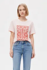 Remera de manga corta color azul con estampa frontal oscura de una ballena decorada con motivos florales.