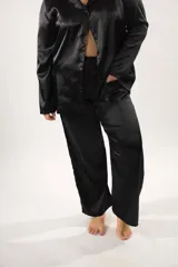 Pijama de seda color negro, compuesto por una camisa de manga larga con solapas y botones frontales, y un pantalón largo de corte recto y holgado.