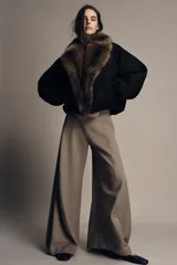 Chaqueta bomber negra de corte corto y diseño abullonado, con cuello de solapa amplio en pelo sintético marrón. Cuenta con mangas largas y cierre frontal.