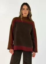 Sweater de punto con diseño color block en tonos gris oscuro, negro y gris claro. Presenta cuello alto, mangas largas y un corte holgado.