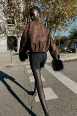 Falda pantalón negra de tiro medio con cierre frontal y hebilla metálica. Presenta bolsillos delanteros y falsos bolsillos de vivo en la espalda.