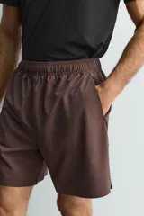 Pantalones deportivos cortos de Zara Athleticz, confeccionados en tejido técnico ligero y elástico. Presentan cintura elástica ajustable con cordón interior, bolsillos frontales, bajo con perforaciones decorativas y aberturas laterales, con detalle de logo estampado en la pierna.