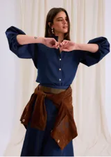 Camisa de jean azul con cuello mao, cierre frontal con botones y mangas tres cuartos abullonadas con puños elásticos.