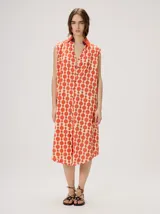 Vestido midi camisero sin mangas, de corte recto y holgado. Cuenta con cuello camisero liso en color naranja y cierre frontal parcial con botones. Presenta un estampado geométrico psicodélico en tonos naranja y beige.