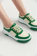 Zapatillas bajas de cuero sintético color crema con detalles en verde pastel y suela celeste.