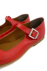 Zapato tipo Mary Jane color rojo, de cuero, con punta redondeada y tira sobre el empeine con hebilla metálica cuadrada.