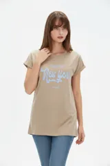 Remera de algodón color beige, de manga corta con vuelta, cuello redondo y corte holgado. Cuenta con un estampado frontal con la inscripción "Manhattan New York East Coast" en tonos celestes.