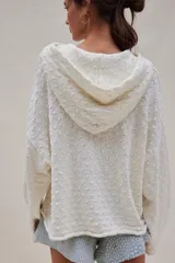 Hoodie blanco de tejido texturado y calado, con amplio calce, mangas anchas, bolsillo canguro y capucha.