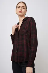 Camisa de manga larga con estampado tartán en tonos verde, gris y blanco, con cuello clásico, cierre frontal con botones, bolsillo en el pecho y corte regular.