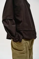 Camiseta oversize de cuello redondo y manga larga con puños abotonados. Confeccionada en algodón, presenta un diseño con combinación de tejidos a tono y bajo asimétrico.