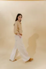 Pantalón de jean gris oscuro, estilo sastrero de tiro medio bajo y corte ancho (wide leg). Presenta costuras marcadas en el frente y un cinturón trenzado marrón con hebilla metálica.