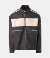 Campera estilo racing confeccionada en poliuretano, con diseño bicolor en negro y beige. Presenta cuello alto con botón a presión, cierre frontal metálico, panel frontal contrastante y franjas laterales deportivas.