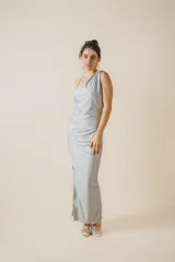Vestido largo fit al cuerpo color plateado con un solo hombro, diseño fruncido en el lateral, tajo lateral en la falda y abertura en la espalda.