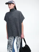 Chaleco tipo poncho de tejido de punto grueso en color gris, con cuello alto tipo polera y diseño holgado con laterales abiertos.