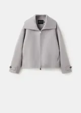 Chaqueta gris de diseño corto y holgado, con cuello alto envolvente, mangas anchas y puños ajustables con tiras y botones. Cuenta con bolsillos laterales y cierre frontal oculto.