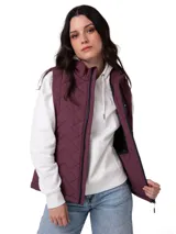 Chaleco acolchado color violeta con diseño de costuras en zigzag. Cuenta con cierre frontal central, cuello alto, bolsillos laterales con cierre y forro interno con logo estampado. Presenta tecnología resistente al viento y al agua con aislamiento térmico reciclado.