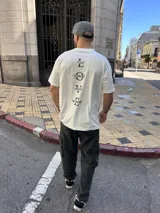 Remera marfil de corte recto con estampado vertical en la espalda con la palabra LOVE y cuatro adjetivos que empiezan con cada letra: Loyal, Observant, Valiant, Enjoyment.