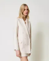 Blazer cruzado de lana color crudo, con solapas, cierre con botones a tono, manga larga con aberturas y bolsillos con solapa.