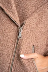 Campera de abrigo color crema, con cuello solapa y cierre asimétrico frontal. Presenta textura bouclé o de lana rizada.