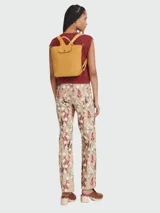 Mochila de cuero de diseño minimalista con solapa frontal, cierre de botón a presión y correas ajustables. Cuenta con asa superior y estructura compacta.