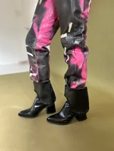 Botas cortas de gamuza color marrón, con taco cuadrado y punta ligeramente elevada. Presentan un detalle de costura trenzada en el borde superior de la caña.