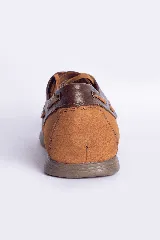 Zapato náutico de cuero azul con detalles en cuero marrón y cordones de cuero.