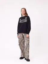 Sweater negro de corte regular con cuello redondo y puños y dobladillo acanalados con detalles de rayas grises. Presenta estampados blancos en el frente con el texto "Rusty Club" y logos de la marca.