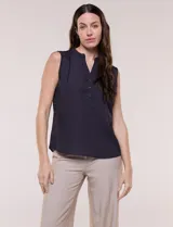Blusa de gasa sin mangas de calce holgado, marca Sioni. Cuenta con cuello cadete, abertura frontal en V con media cartera de botones, espalda con canesú y pliegue central, y ruedo redondeado.