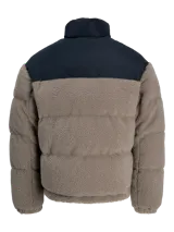 Campera puffer con diseño de bloques de color, combinando tejido teddy en tono arena y paneles negros en los hombros. Presenta cuello alto, cierre frontal y diseño acolchado.