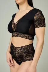 Conjunto de lencería negro compuesto por un bralette de lycra y microtul con detalles de encaje en escote, bajo busto y mangas cortas, y una bombacha hipster de tiro alto confeccionada íntegramente en encaje.