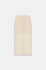 Falda midi color beige claro, de tiro alto, con cintura elástica y diseño combinado: la parte superior es opaca y la inferior es de tejido transparente o semitransparente.
