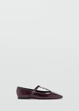 Zapato plano tipo Mary Jane, color bordó, de punta fina y tira en forma de T con hebilla metálica dorada ajustable.