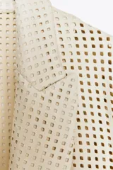 Blazer color crudo con diseño troquelado, cuello solapa, manga larga y bolsillos delanteros de plastrón.